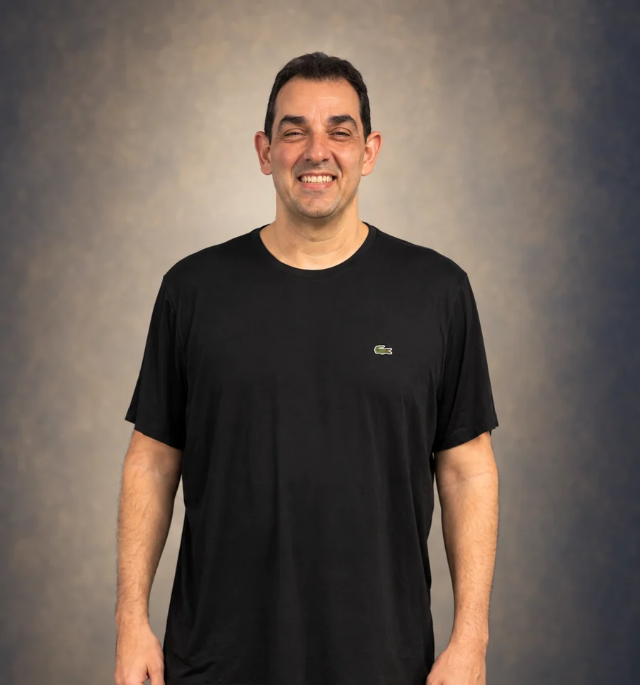 Victor Mirshawka Jr., sorrindo, de camiseta preta, em retrato de estúdio